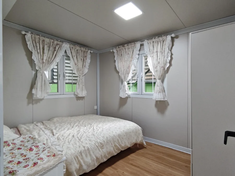 20ft container house bedroom with soft white bedding and bedside table