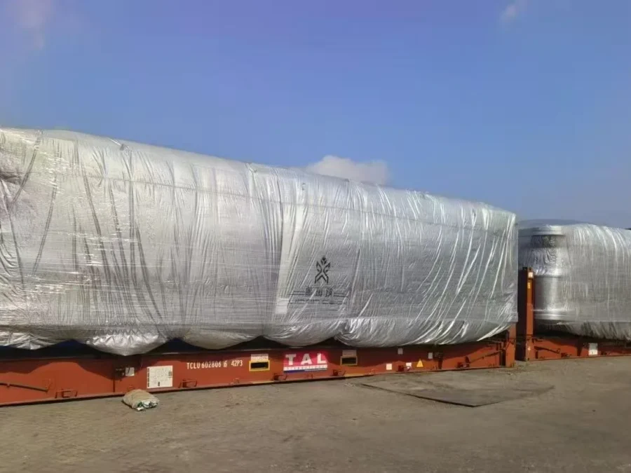 Flat-pack container house modules tarp-wrapped and strapped for overseas shipping